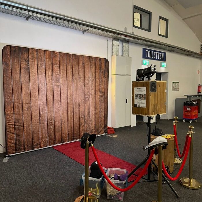 Fotobox-Aufbau mit Holz-Hintergrund und rotem Teppich in großer Location